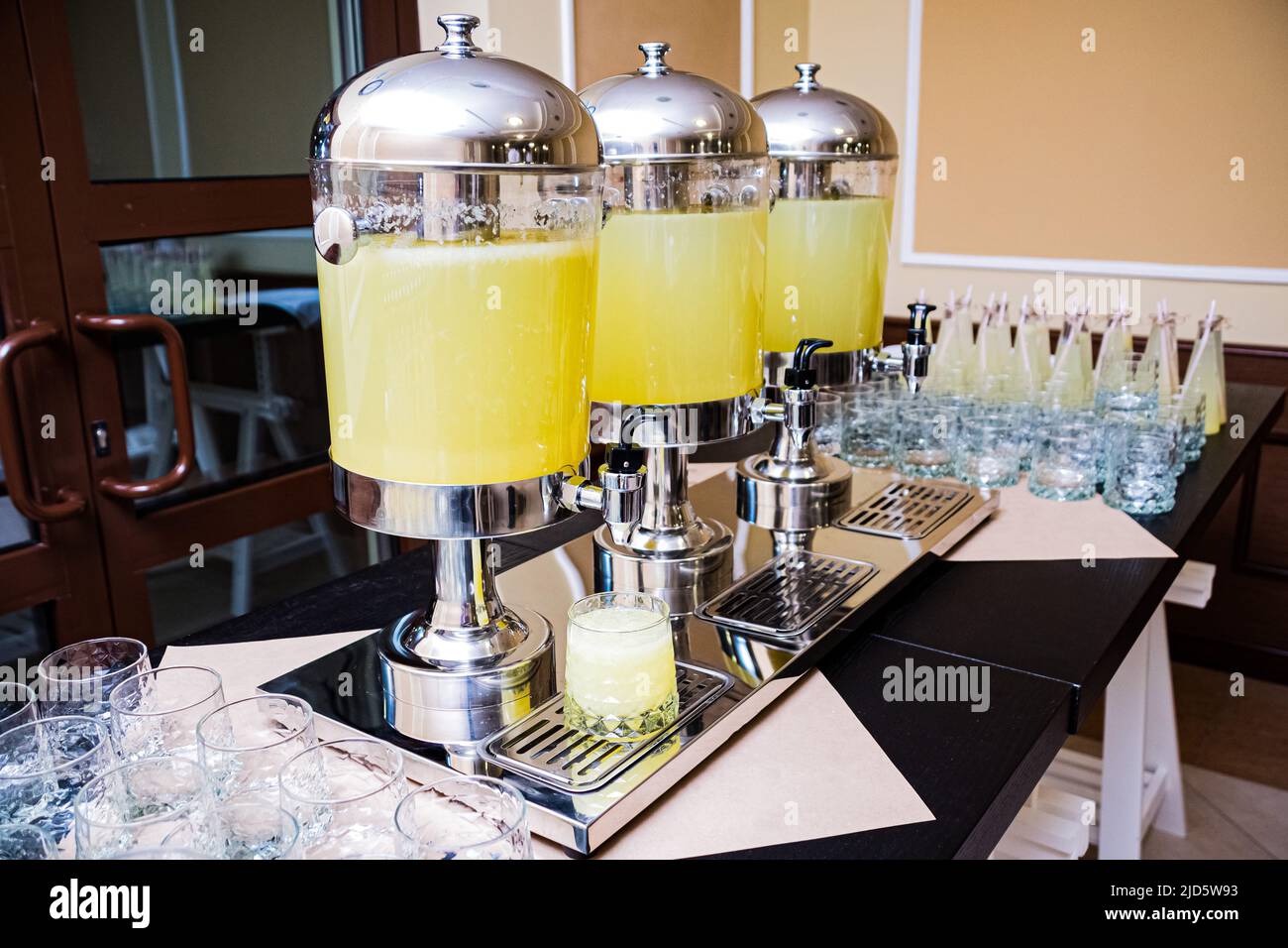 Three beverage dispensers with lemonade standing on the table. Refreshment drinks. Self serving
