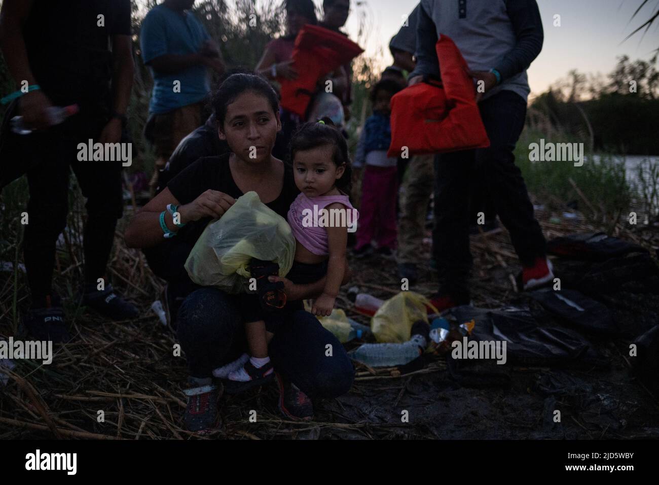 Maria, an asylum-seeking migrant from Honduras, holds her one-year-old daughter Mariette as they take shelter on a sandbar before being smuggled across Rio Bravo del Norte, also known as the Rio Grande river, into Roma, Texas, U.S. from Ciudad Miguel Aleman, Mexico June 17, 2022. Picture taken June 17, 2022. REUTERS/Adrees Latif Stock Photo
