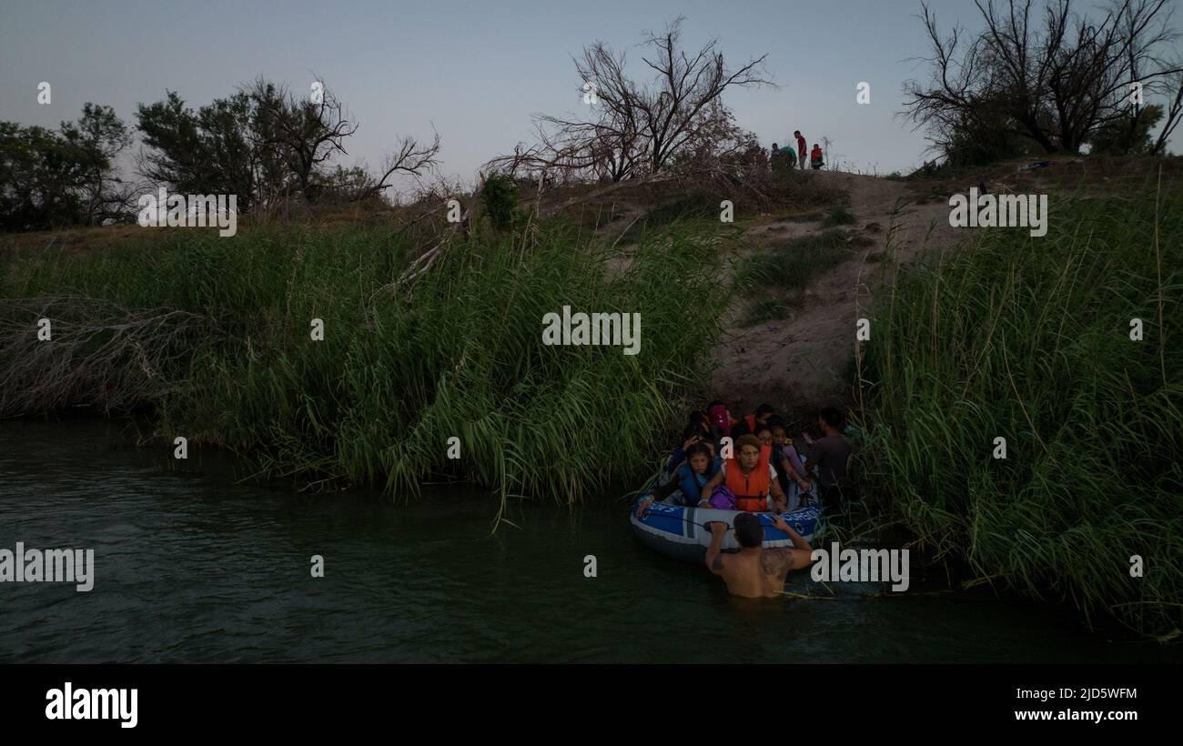 A scout keeps watch in the background as a smuggler prepares to launch a raft with asylum-seeking migrants from the bank of the Rio Bravo del Norte, also known as the Rio Grande River, in Ciudad Miguel Aleman, Mexico June 17, 2022. The migrants, most from Central America, would be transferred onto a sandbar in the middle of river before entering the United States in Roma, Texas. Picture taken with a drone on June 17, 2022. REUTERS/Adrees Latif Stock Photo