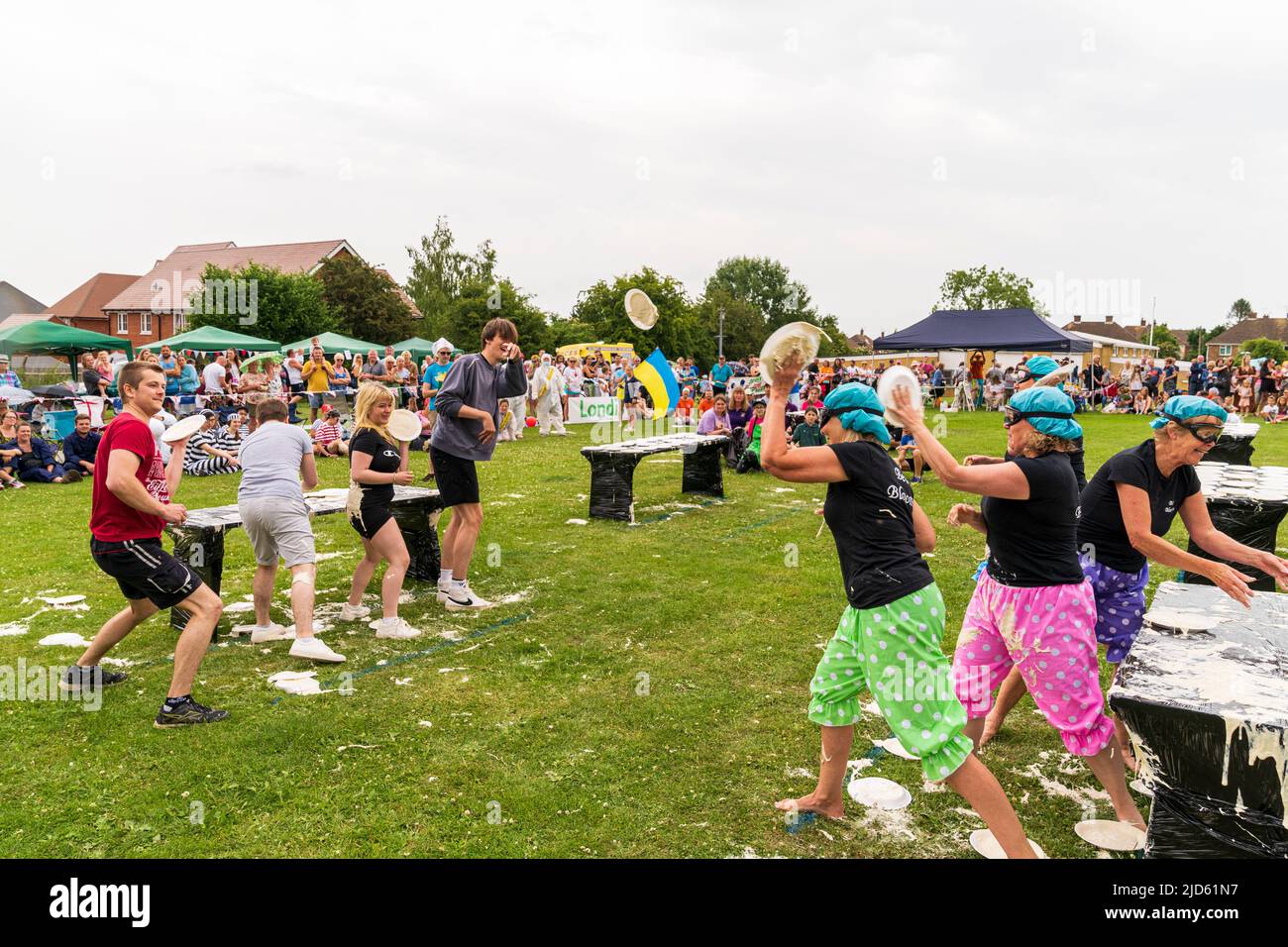 Two teams of four people in fancy dress throwing custard pies at each