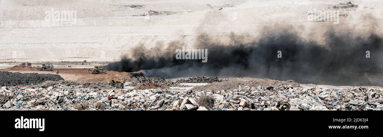 Fire at landfill site. Panorama of black smoke over burning old tyres and piles of garbage Stock Photo