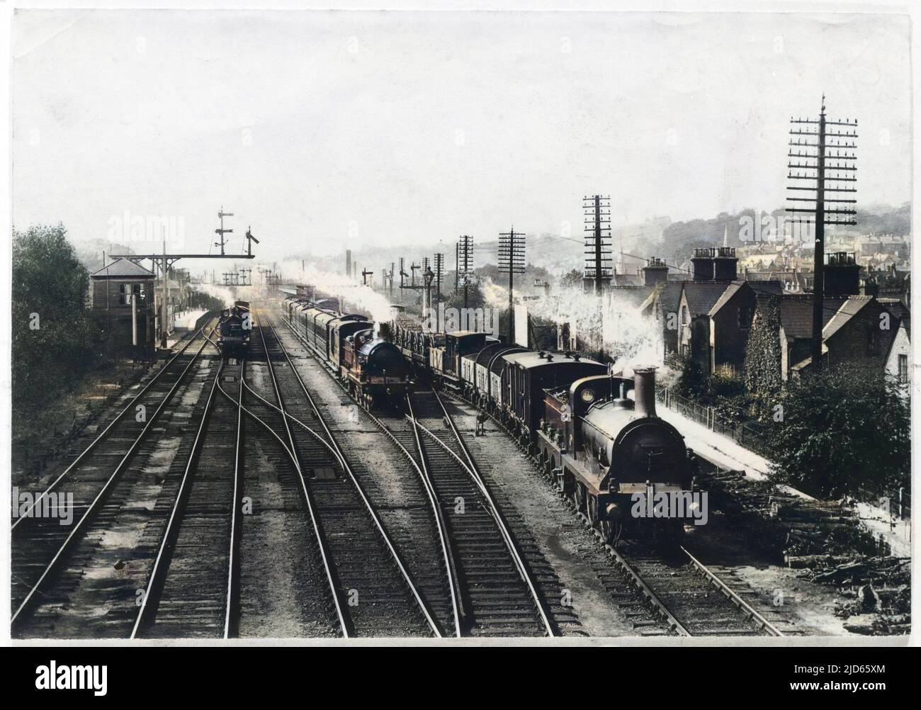 A goods train waits on one track to let the passenger train go through, while a third train approaches through the station at Redhill, Surrey. Colourised version of : 10003799       Date: 1909 Stock Photo