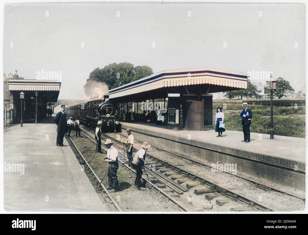 Navvies at work on the line at Upminster Station in the London Borough of Havering, Greater London, not far from the border with Essex. Two passengers wait on the far platform for their train to arrive. Colourised version of : 10006466       Date: 1908 Stock Photo