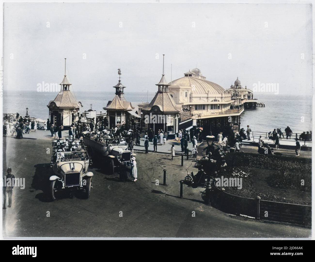 Charabancs drop their passengers at the entrance to the pier in Eastbourne, East Sussex. Colourised version of : 10006463       Date: 1925 Stock Photo