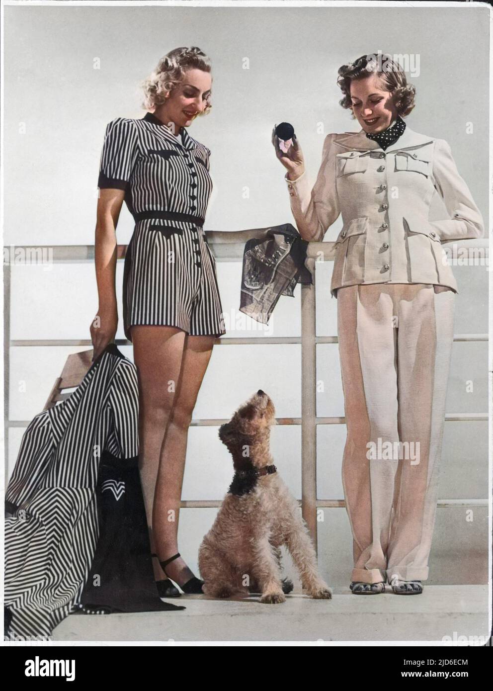 Striped playsuit with shorts with matching 3/4 length coat or a linen suit with trousers & jacket with large patch pockets. A wire-haired fox terrier sits nearby. Colourised version of : 10144354       Date: late 1930s Stock Photo