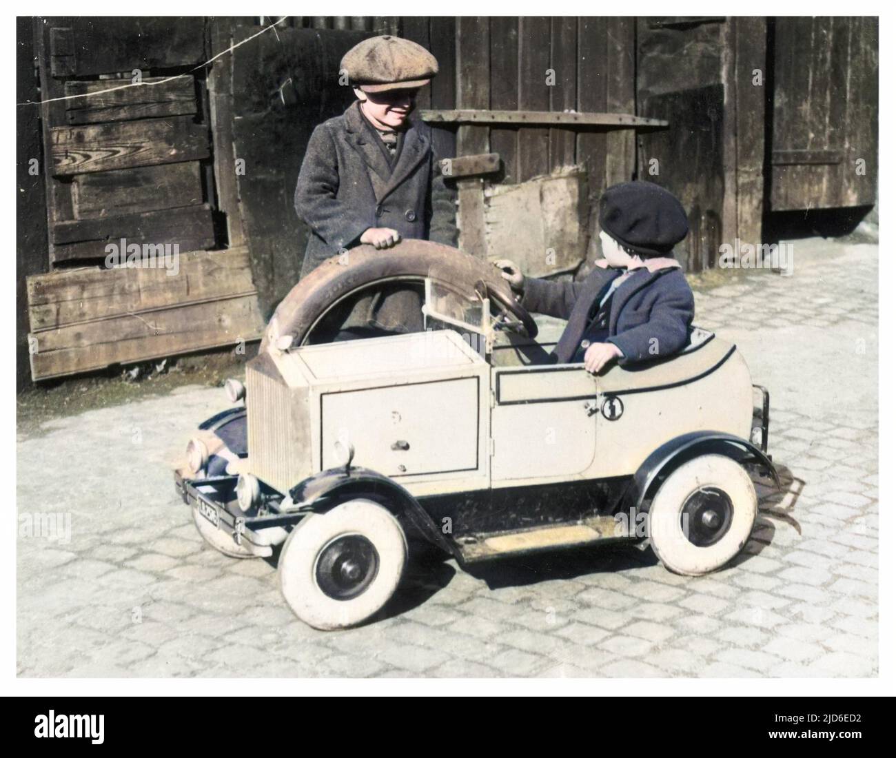 Two boys play with a minature Rolls Royce Colourised version of : 10145120       Date: 1930s Stock Photo