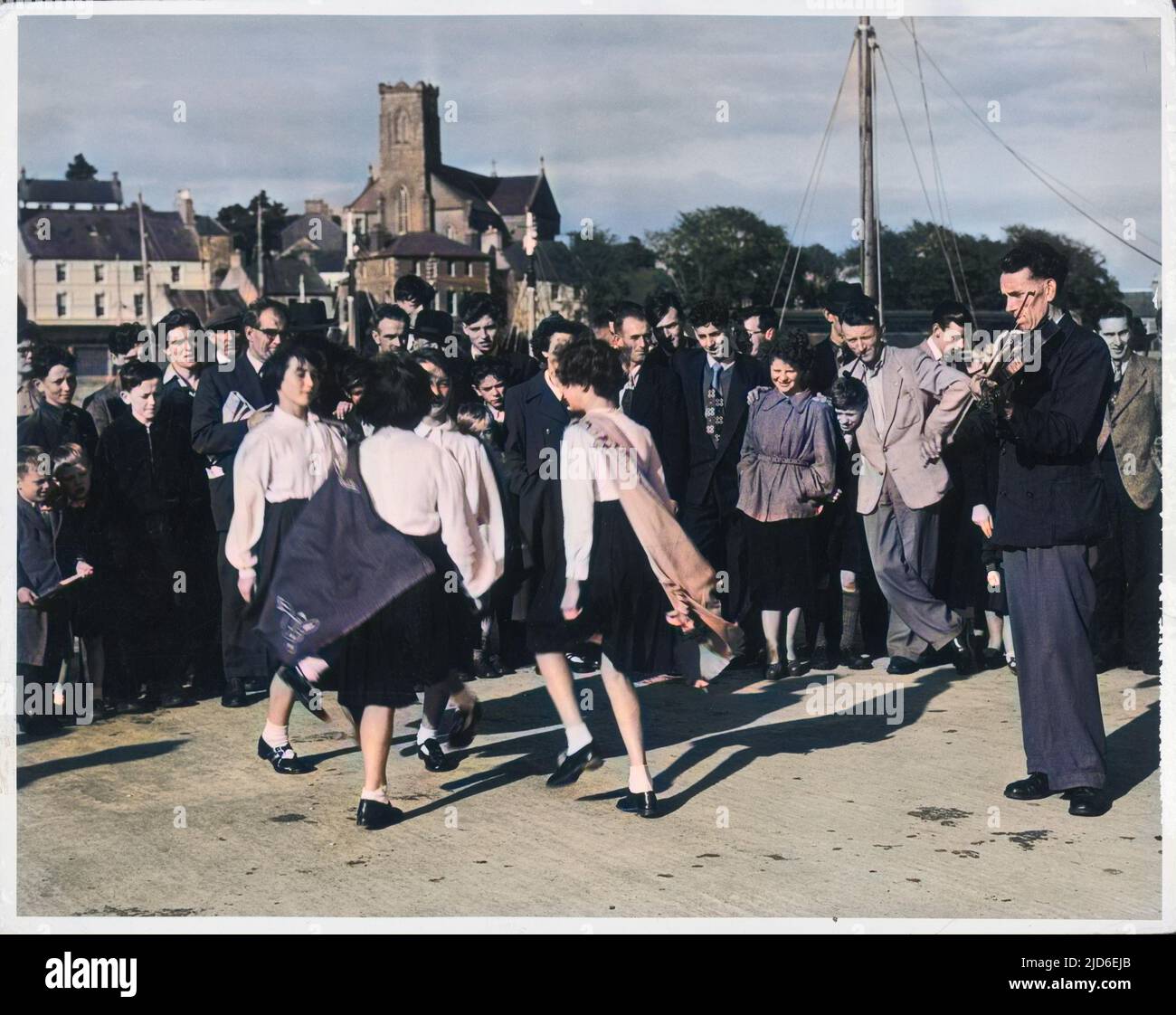 A crowd watching girls performing traditional Irish dancing at Killybegs, County Donegal, Ireland. Colourised version of : 10152251       Date: 1950s Stock Photo