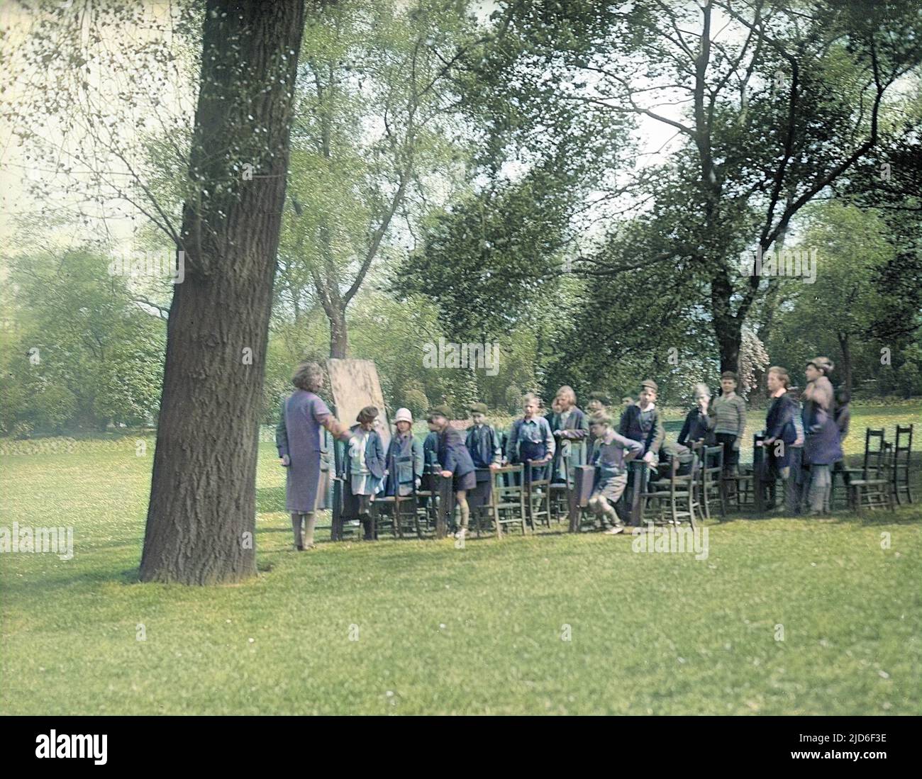 An open air school lesson under some trees in St. James's Park, central London, England. Colourised version of : 10162504       Date: early 1930s Stock Photo