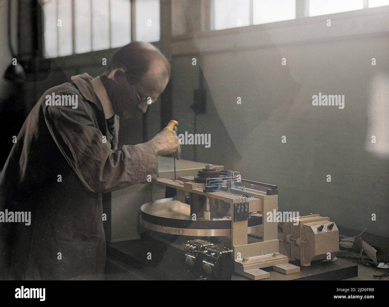 An engineer testing equipment at Dollis Hill telephone exchange, London. Colourised version of