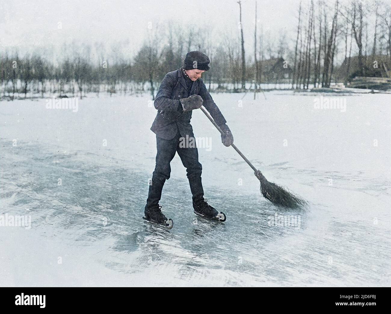 A man on ice skates, sweeping the ice with a broom. Colourised version