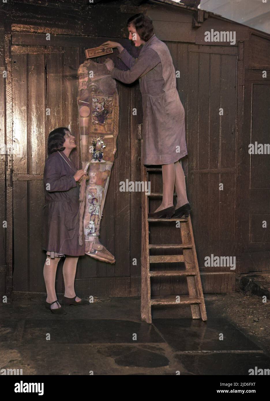 Two young women hanging up a huge Christmas stocking stuffed with