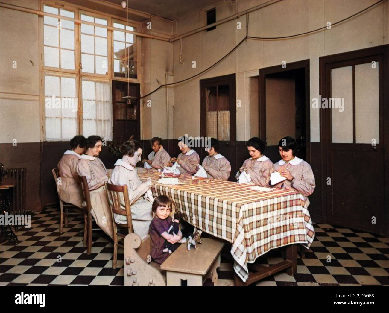 A group of women doing needlework around a table, with only one child