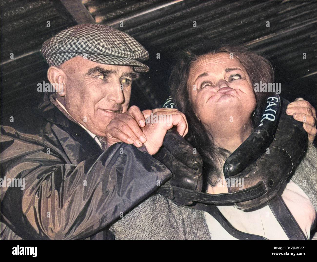 A woman gurner pulls a truely awful face through a leather ring during the gurning contest at Egremont Crab Fair, Whitehaven, Cumbria, England. Colourised version of : 10185601       Date: 1980s Stock Photo