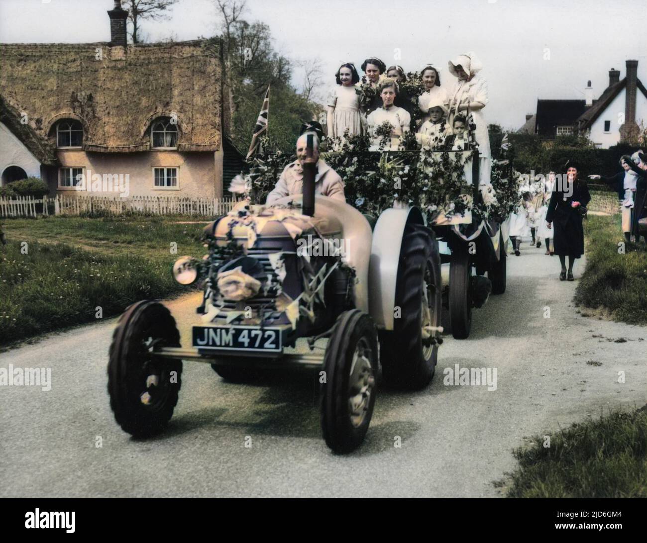 Traditional May Day festivities at Ickwell, Bedfordshire, England. Here, the May Queen arrives on the village green in luxury - by tractor! Colourised version of : 10184372       Date: 1950s Stock Photo