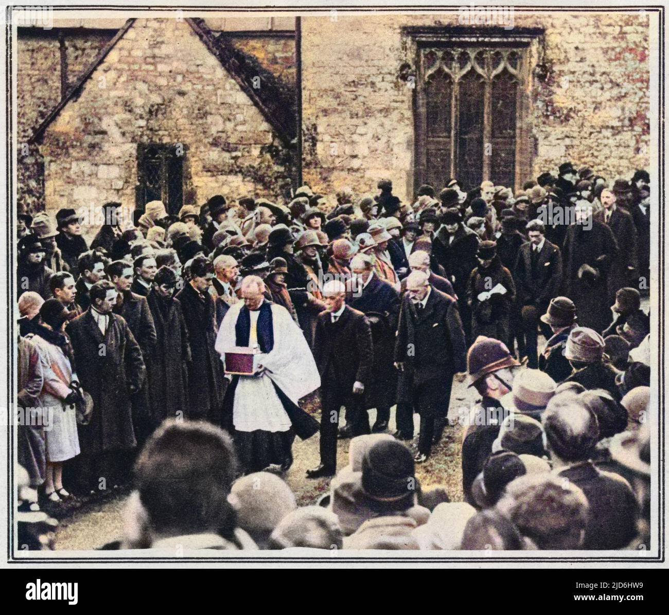 The burial of Thomas Hardy's heart among his own people: the vicar of Stinsford in Dorset ('Mellstock' of 'Under the Greenwood Tree') bearing the casket containing it, with mourners including the novelists brother, from church to grave. Hardy's ashes were interred at Westminster Abbey in Poet's Corner. Colourised version of: 10224231       Date: 1928 Stock Photo