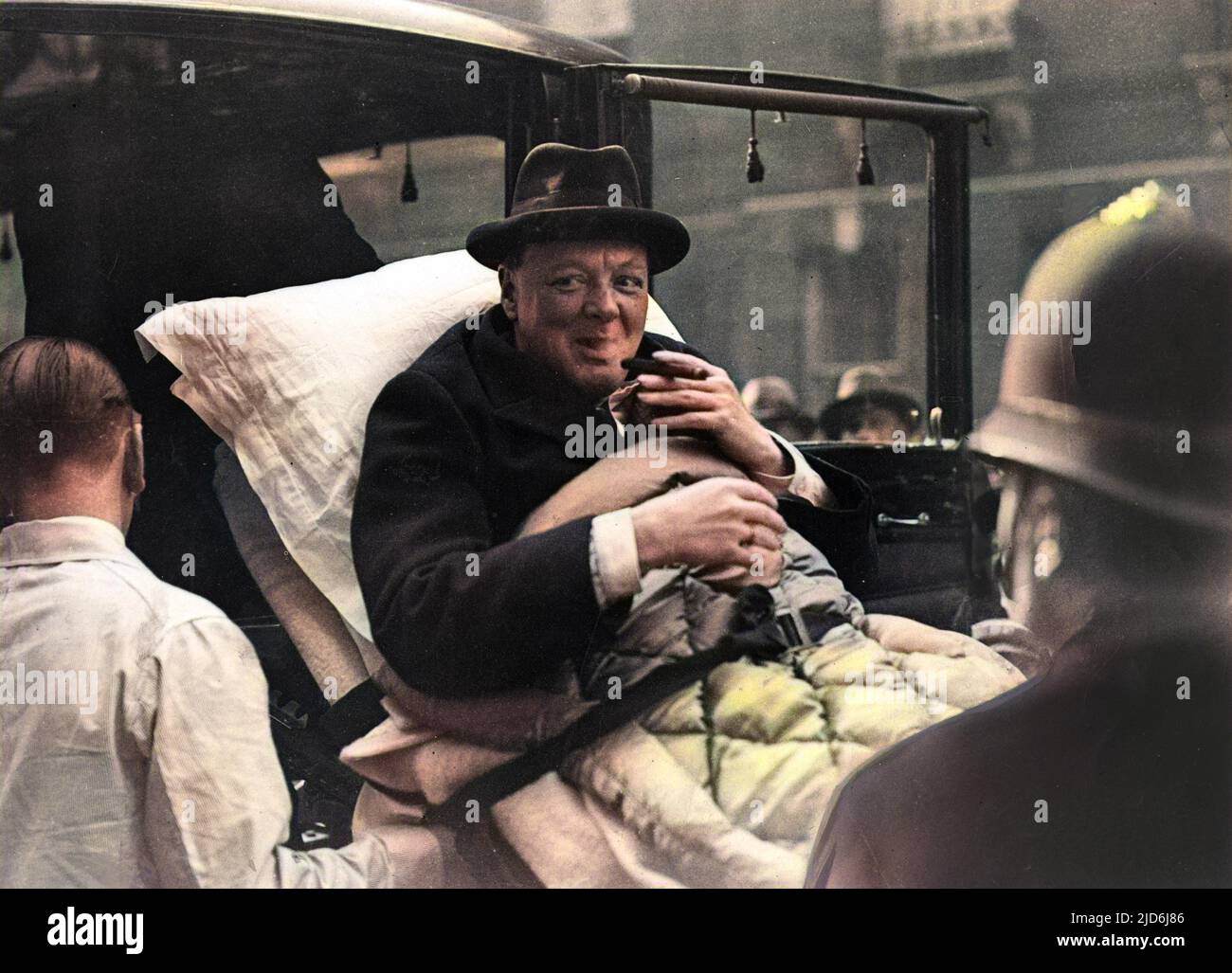 Winston Churchill (1874-1965), English politician, having a cheeky puff on his cigar whilst being stretchered from his London flat to a West End nursing home via ambulance, having been taken ill with paratyphoid. Colourised version of: 10529270       Date: 1932 Stock Photo