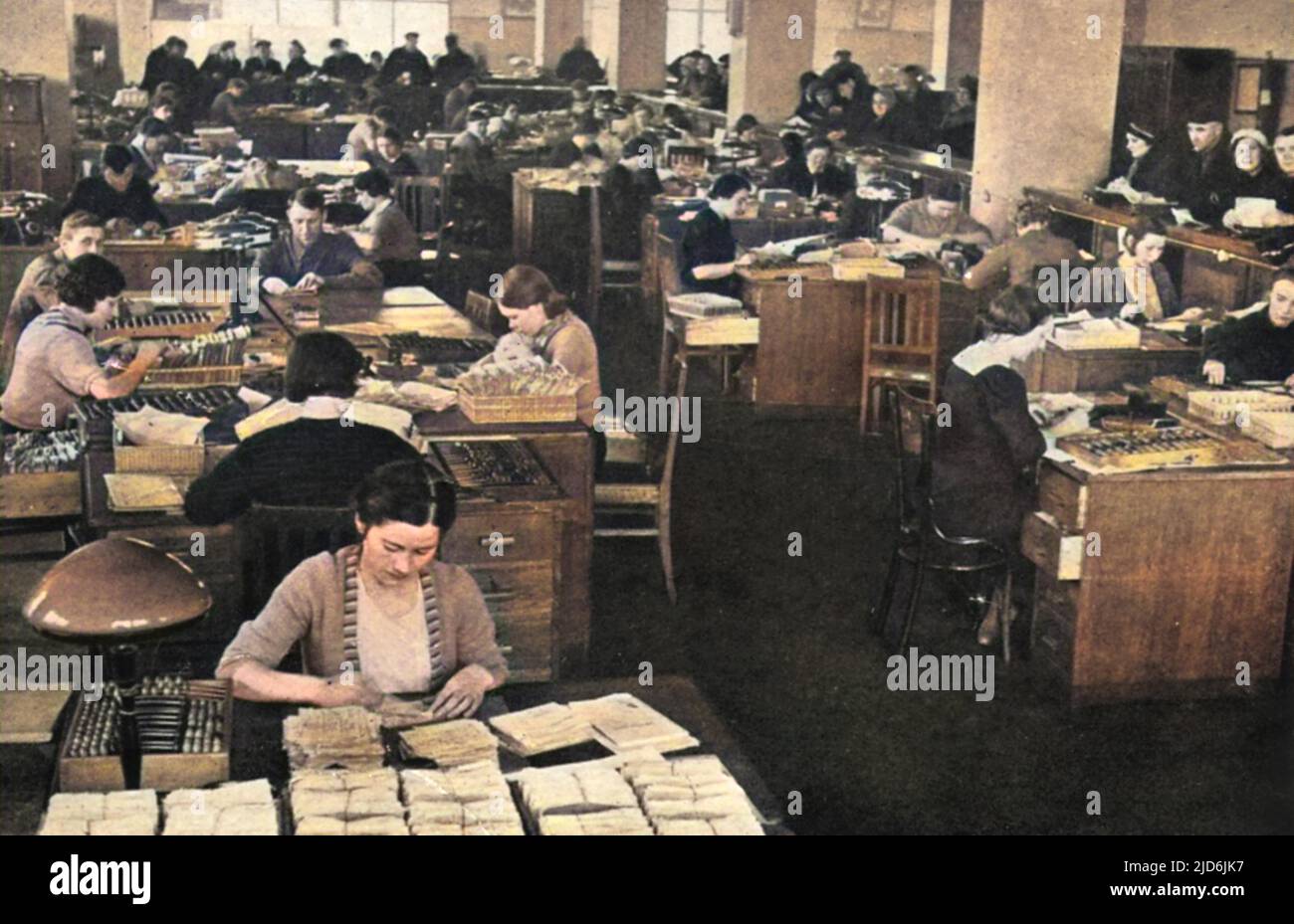 Registering the deposits of Soviet workers in the State Bank of the U.S.S.R in 1939.  On the right, depositors can be seen at a counter waiting their turn while men and women clerks are busily engaged in banking work. Colourised version of: 10582993       Date: 1939 Stock Photo