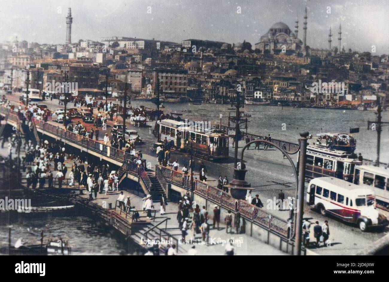 A view across the Galata Bridge and Golden Horn, with motorbuses, trams, cars and pedestrians packing the crossing. Colourised version of: 10285127       Date: circa 1930s Stock Photo