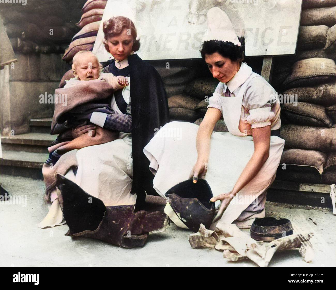 Nurses from The Great Ormond Street Children's Hospital examine fragments from the bomb which struck the building but (thankfully) caused no loss of life - September, 1940. The sign reads: Dispensary and Almoner's Office Colourised version of: 10922935       Date: 1940 Stock Photo