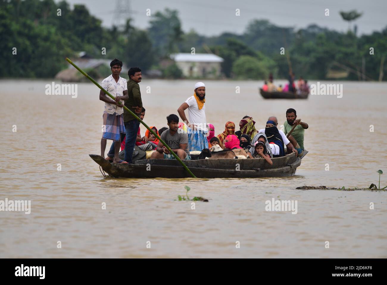 Hojai. 18th June, 2022. Villagers move from a flood affected area to a