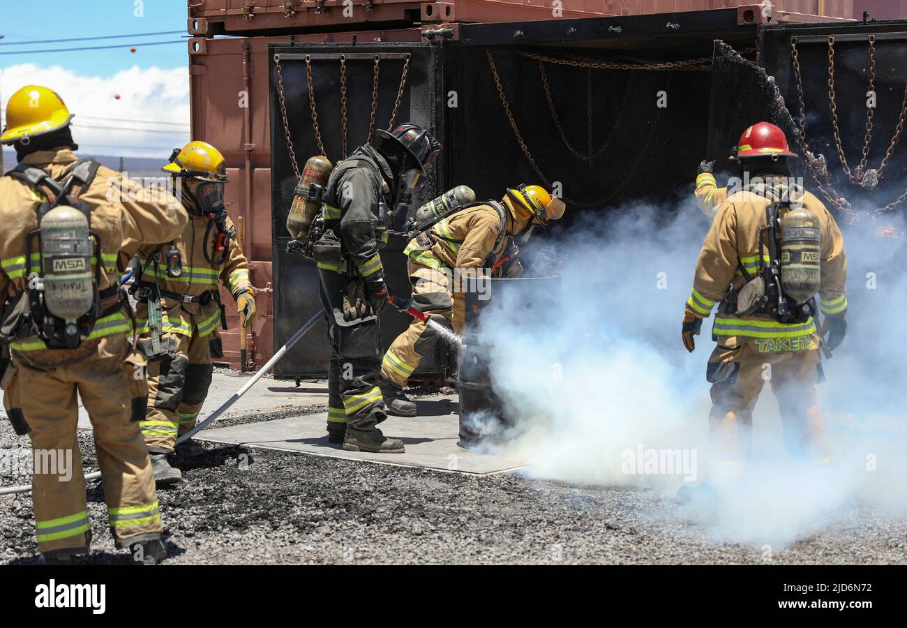 Members of the Pohakuloa Training Area Federal Fire Department (PTA FFD) extinguish a fire during flashover training at Pohakuloa Training Area, Hawaii, June 14, 2022. The PTA FFD hosted the Hawaii Army National Guard firefighting team in flashover training, which taught them how to build confidence using their own gear and control the temperature of a fire. (U.S. Army National Guard photo by Spc. Mariah-Alexsandra Manandic-Kapu) Stock Photo
