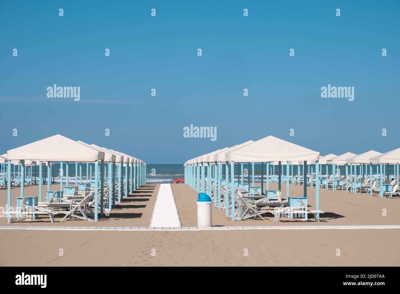 Blue and white beach cabanas lined up and ready for the day's beachgoers in Viareggio, Italy. Stock Photo