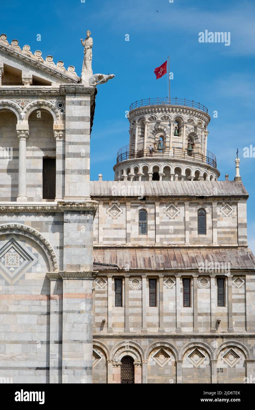 Leaning tower of Pisa peaking from behind Pisa Cathedral with brilliand blue sky. Stock Photo