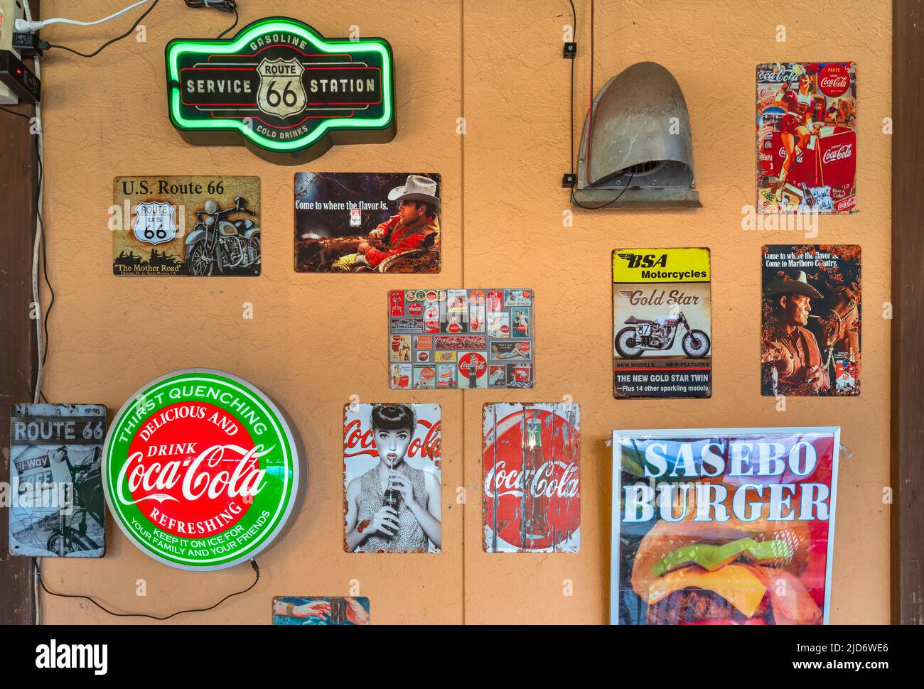 kyushu, japan - december 09 2021: American neon signs of soda brands and route 66 with some rusted metal plates of Marlboro tobacco on the wall of Sas Stock Photo