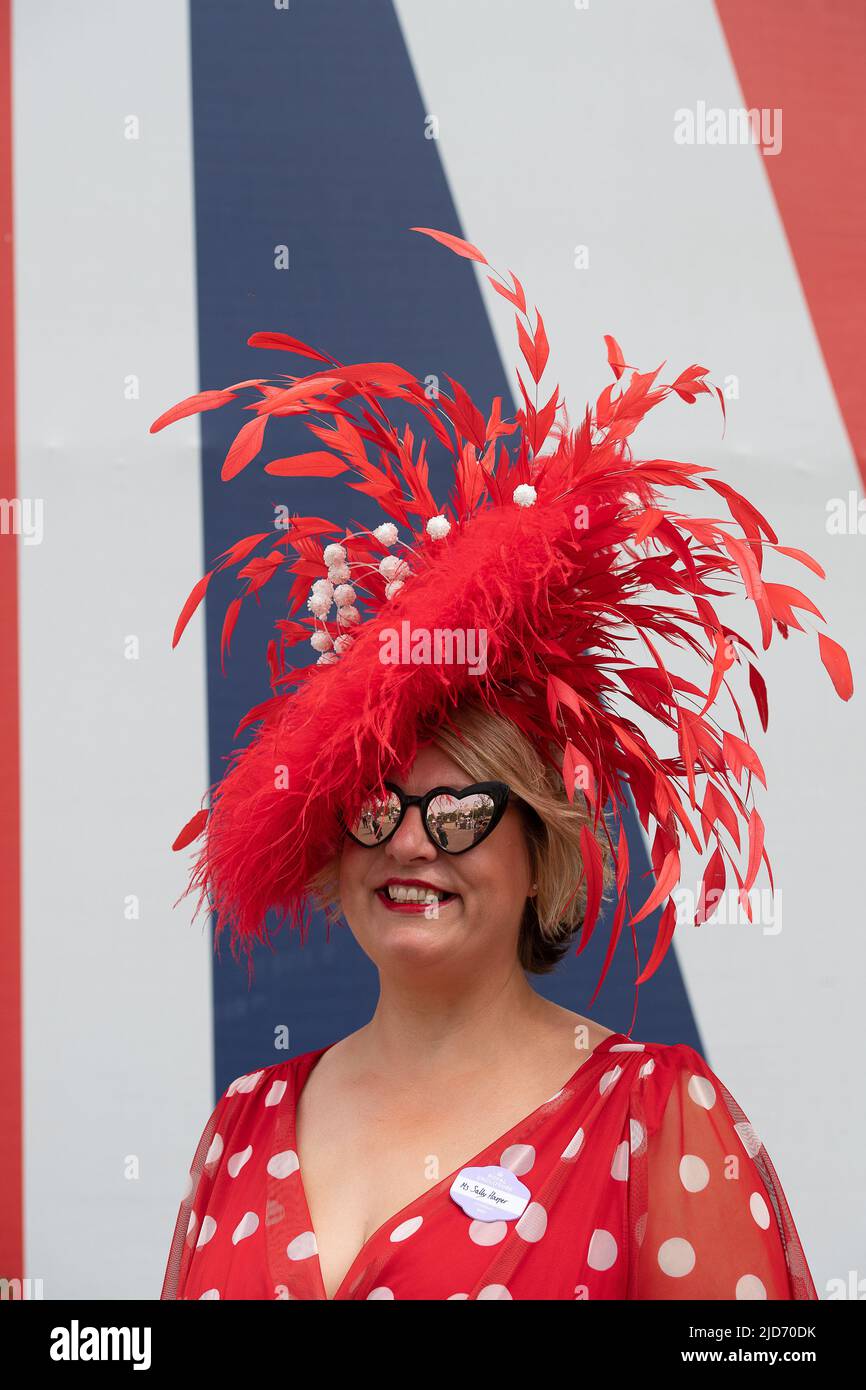 Ascot, Berkshire, UK. 18th June, 2022. Milliner Sally Harper wears one of her red headpieces. Racegoers arriving at Royal Ascot were looking very glamourous for the final day of Royal Ascot. After a week of glorious sunshine there were a few spots of rain this morning so the umbrellas were in action for a while. Credit: Maureen McLean/Alamy Live News Stock Photo