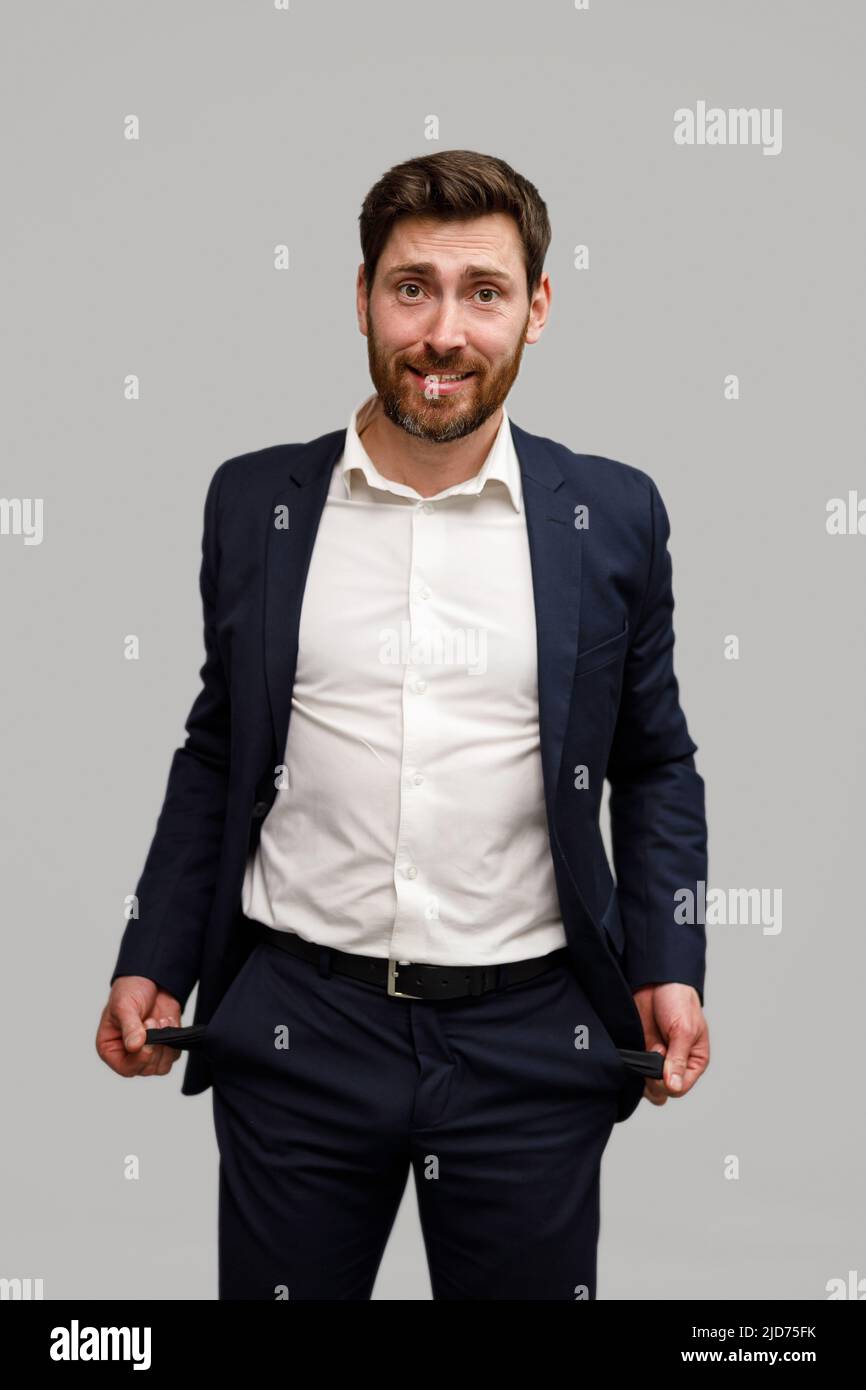 Businessman showing his empty pockets standing on grey studio background Stock Photo