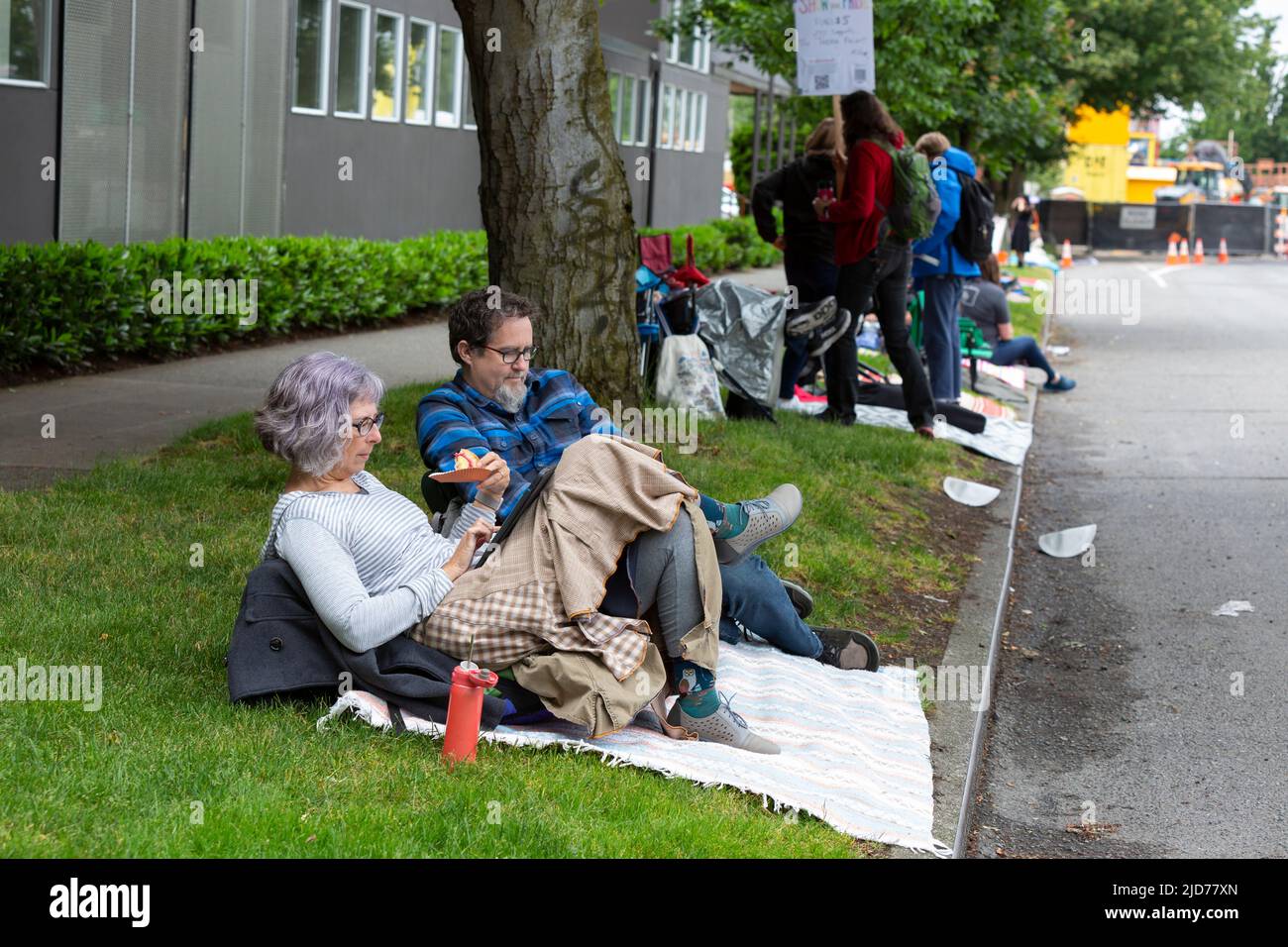 Seattle, Washington, USA. 18th June, 2022. Kristen Dahlquist (left) and Geoff Schemmel relax as they wait for the Fremont Solstice Parade to begin. The iconic, annual parade returned after a three-year hiatus due to the coronavirus pandemic. Credit: Paul Christian Gordon/Alamy Live News Stock Photo