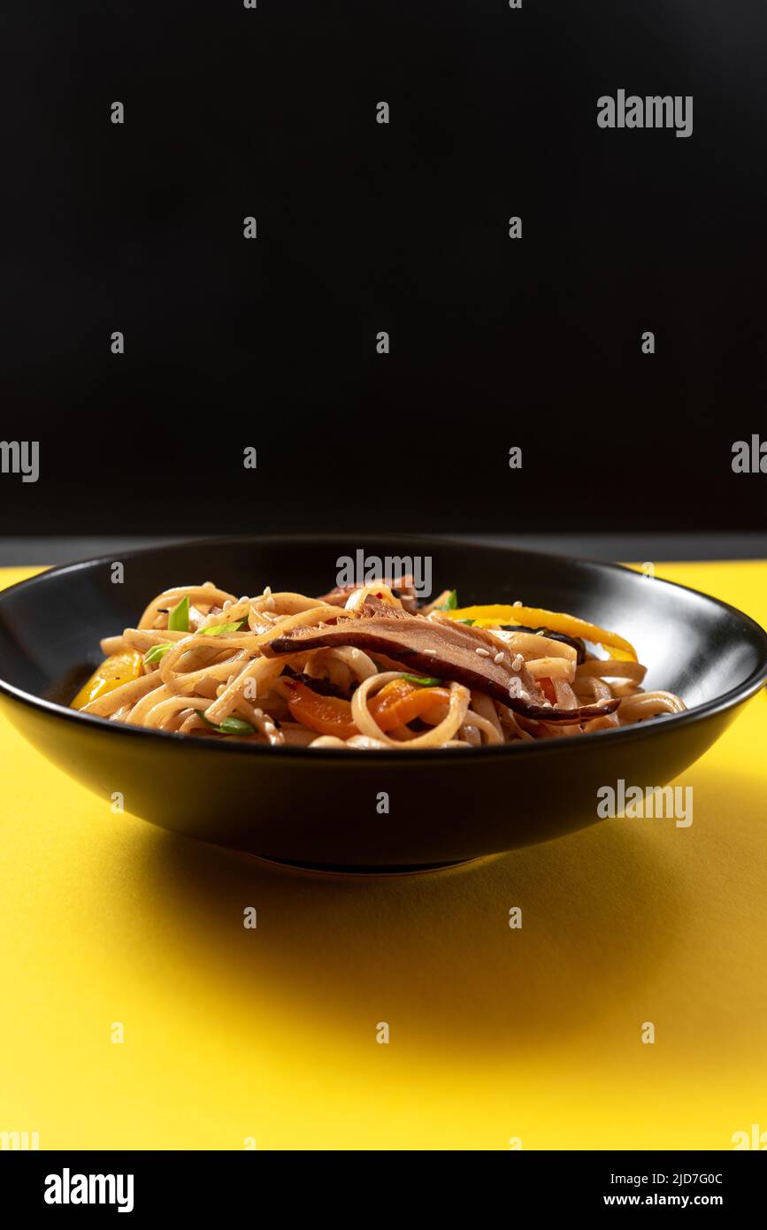 Plate with noodles on a bright yellow background. Stock Photo