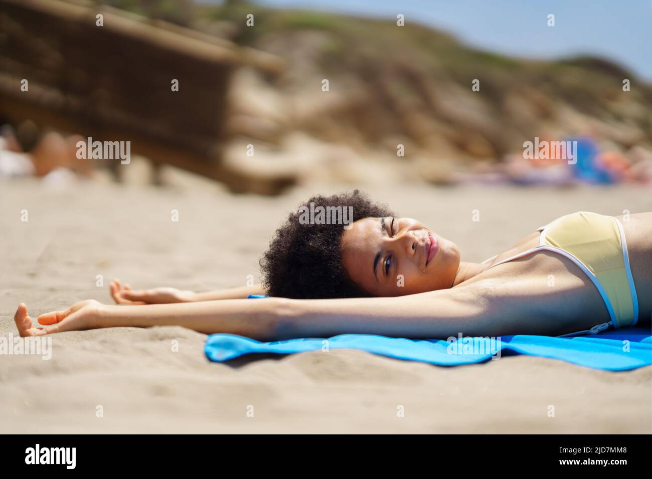 Content young African American woman lying on sandy beach and winking at camera Stock Photo
