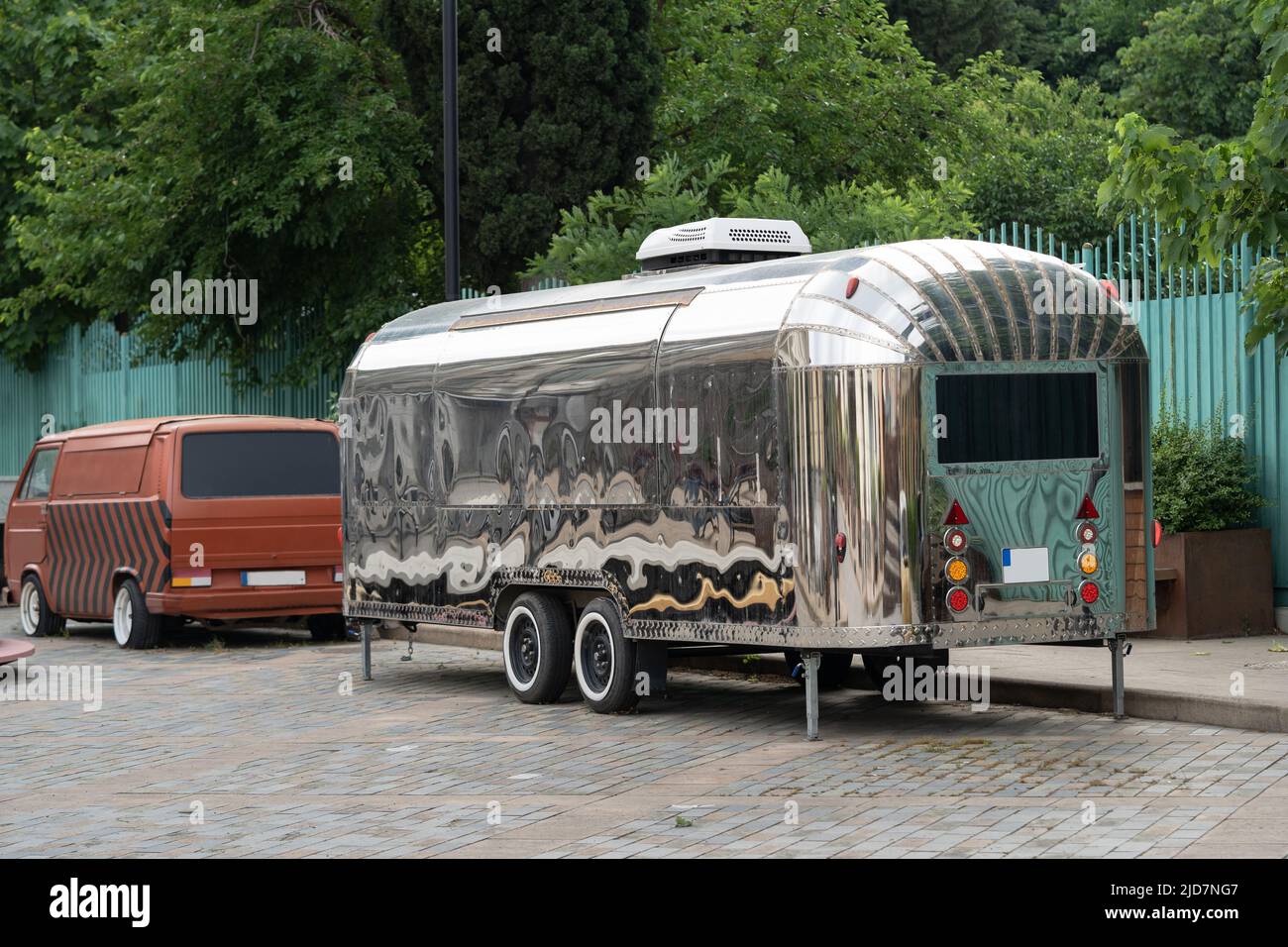 Retro style futuristic silver metal trailer van standing on summer day for fair, festival or event. Stock Photo