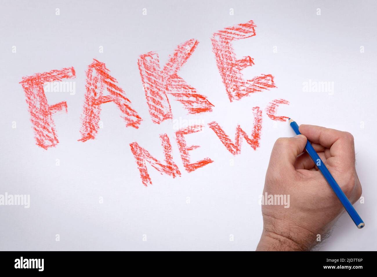Lettering FAKE NEWS. Inscription FAKE NEWS is red, drawn with a blue pencil on a white background. Hand writing lettering FAKE NEWS. Propaganda in media. Substitution of concepts. Handdraw lettering. Stock Photo