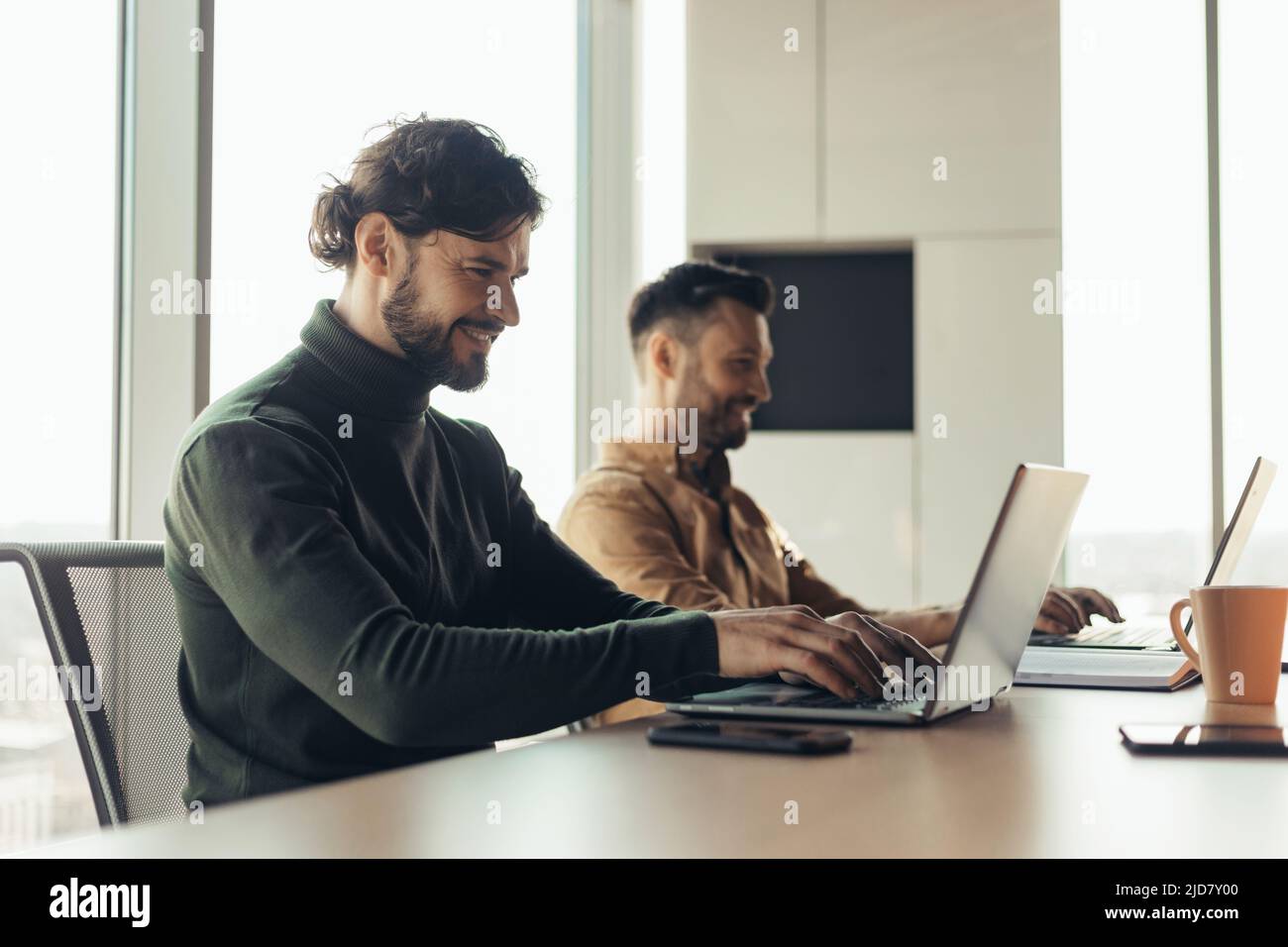 Joyful male coworkers using laptops, working on business project ...
