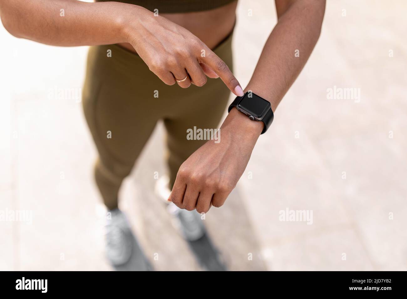 Young black woman using fitness tracker with mockup, checking heart