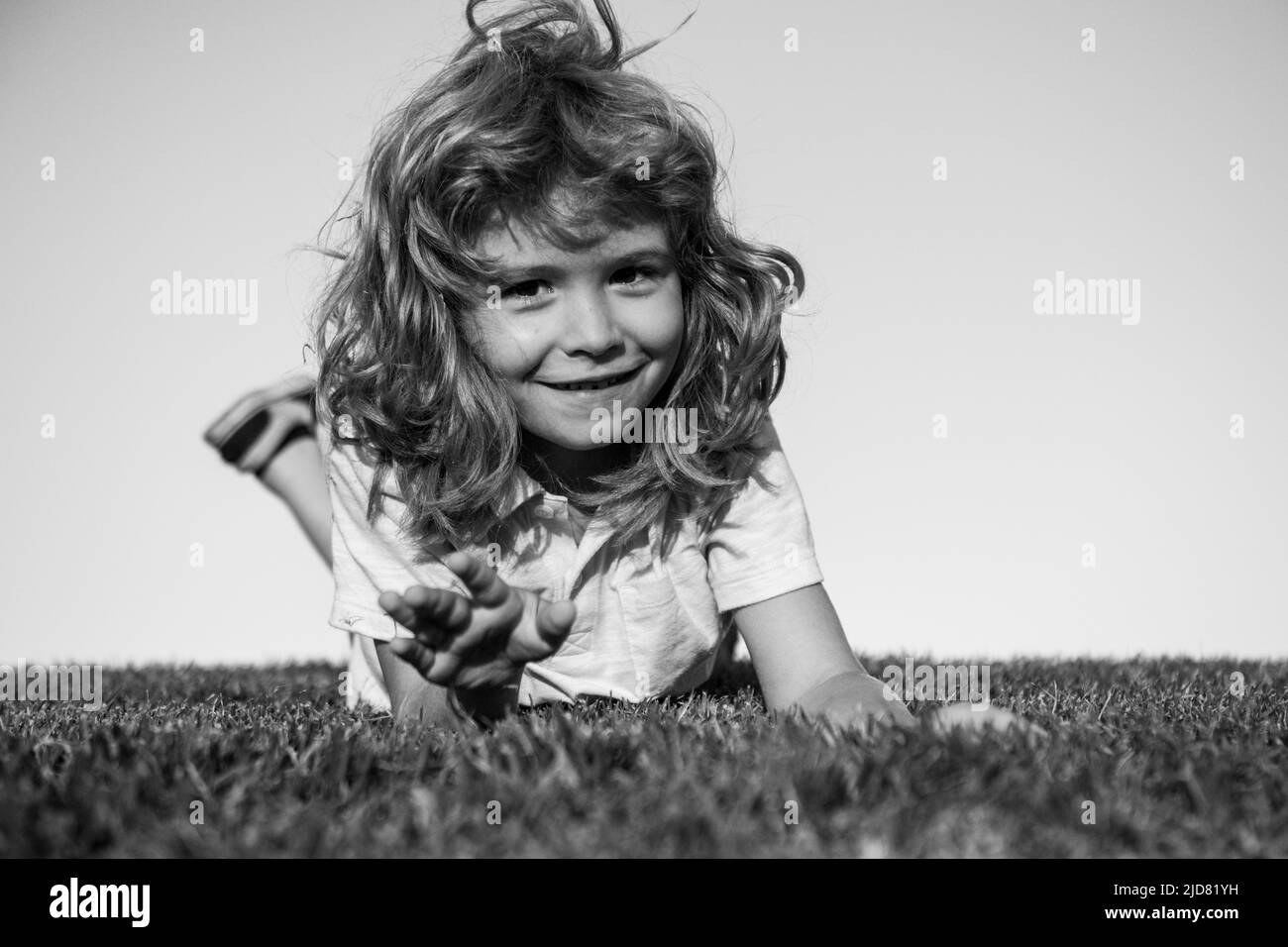 Portrait of a happy smiling child boy playing on grass field. Laughing child. Expressive facial expressions. Stock Photo