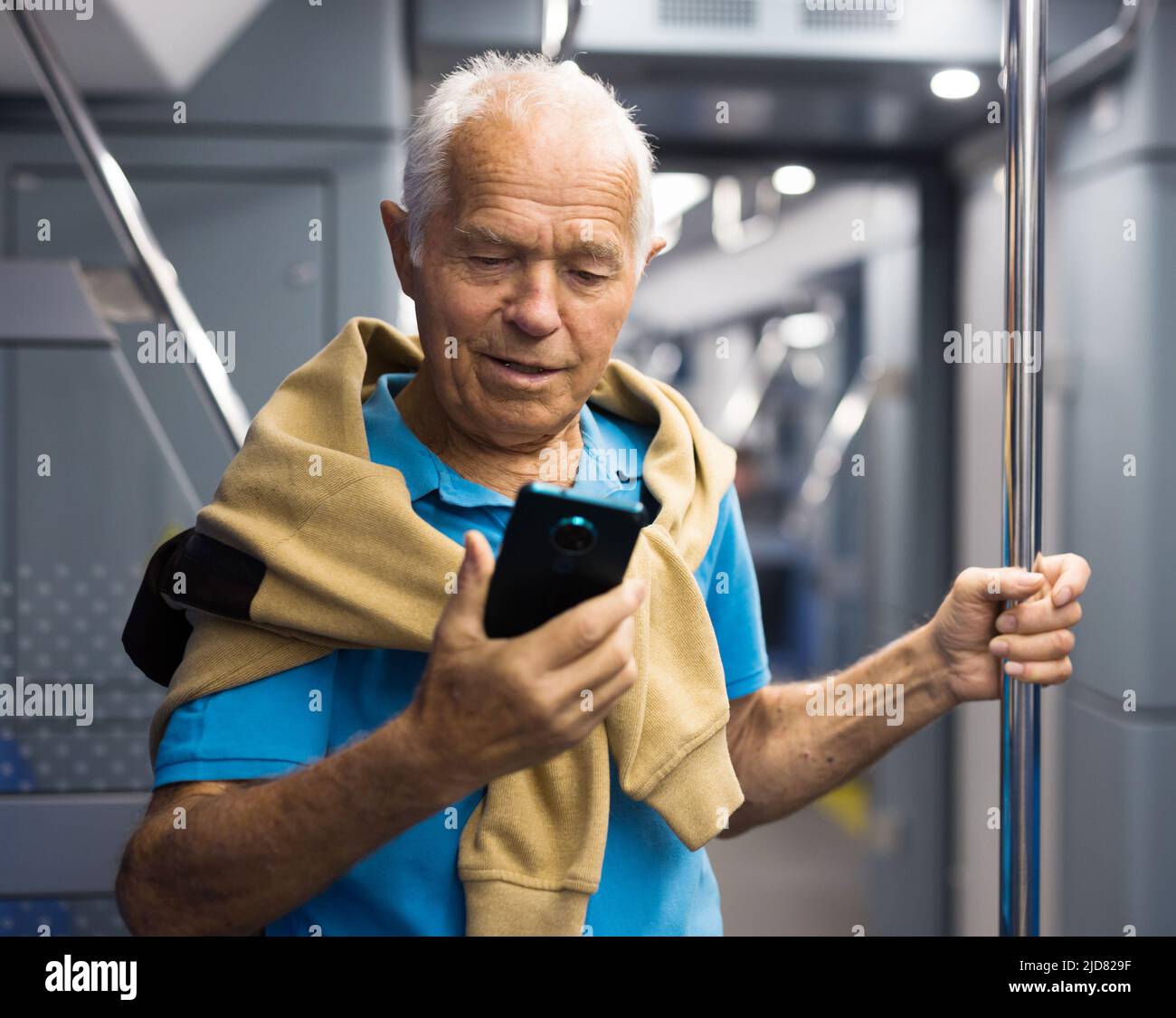 Old man with phone in subway car Stock Photo