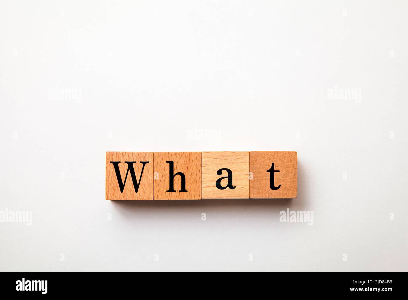 What character. what. Interrogative pronoun. Written on four wooden blocks. White background. Stock Photo