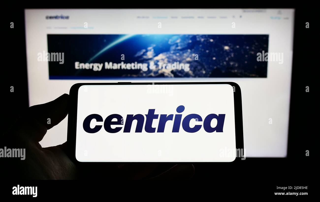 Person holding smartphone with logo of British utility company Centrica plc on screen in front of website. Focus on phone display. Stock Photo