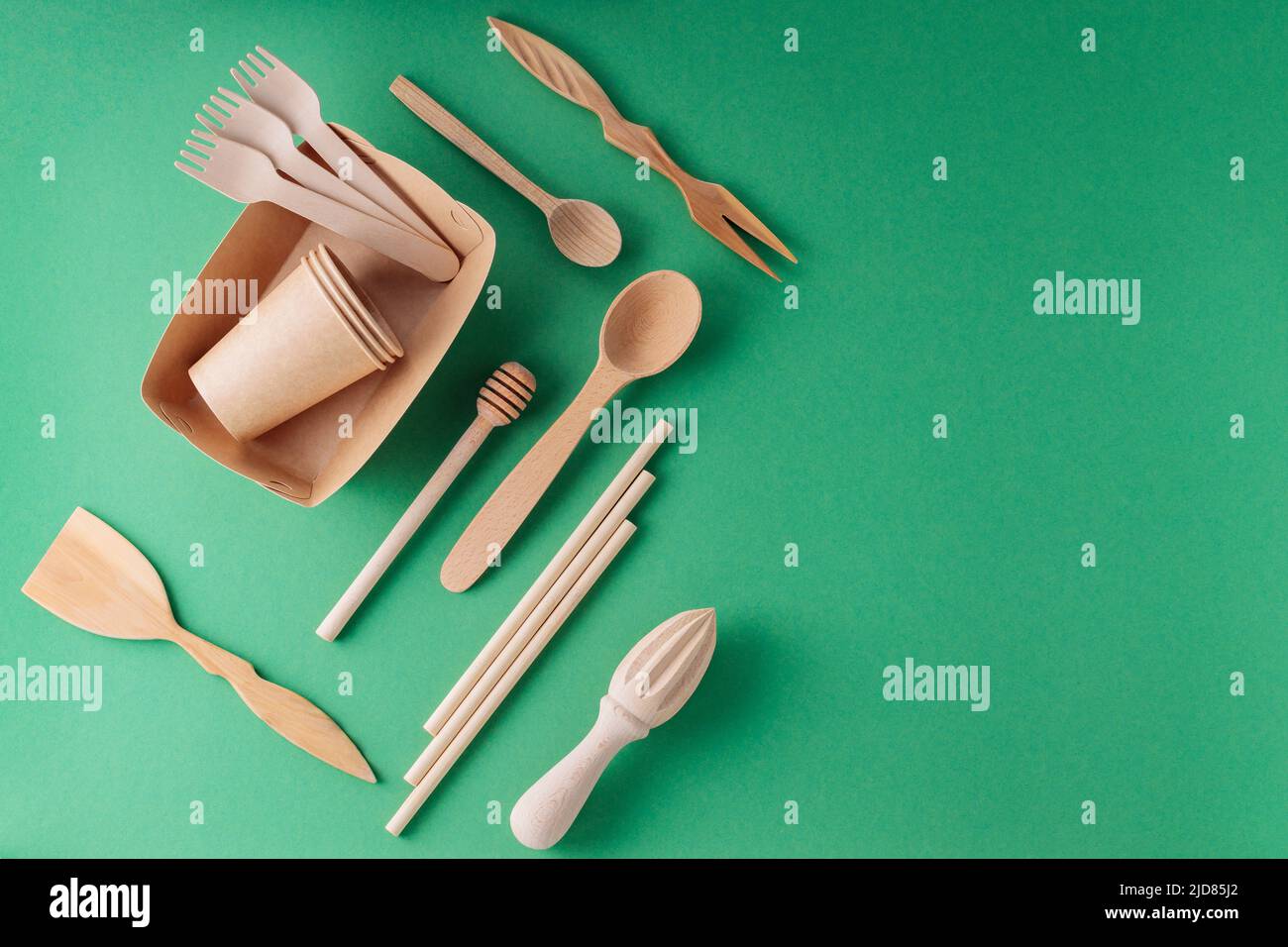 Paper biodegradable tableware and wooden cutlery on a green background ...