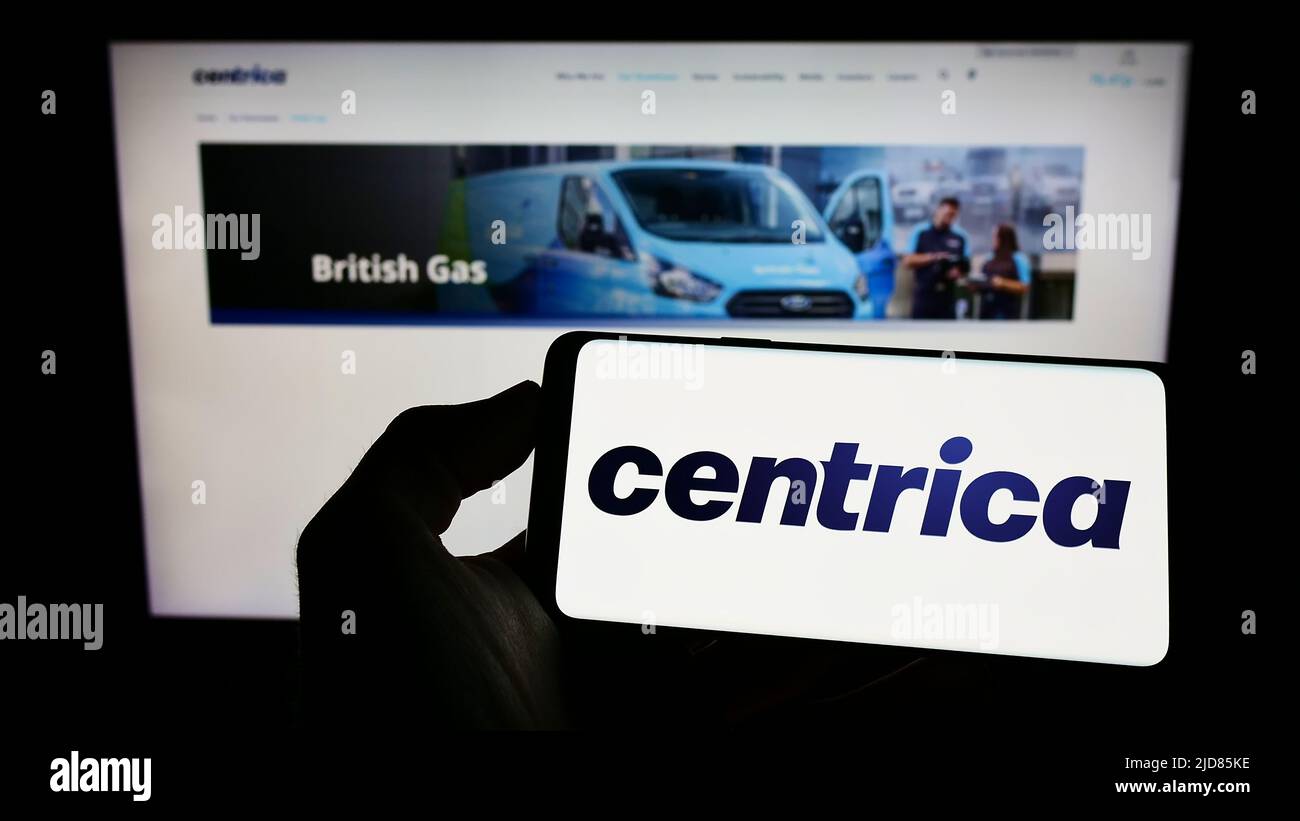Person holding cellphone with logo of British utility company Centrica plc on screen in front of business webpage. Focus on phone display. Stock Photo