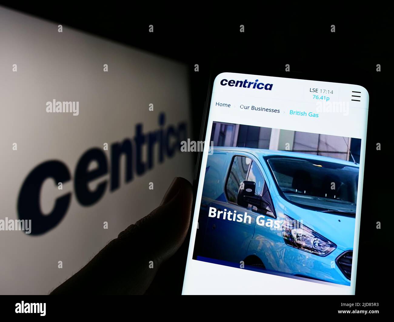 Person holding cellphone with webpage of British utility company Centrica plc on screen in front of logo. Focus on center of phone display. Stock Photo