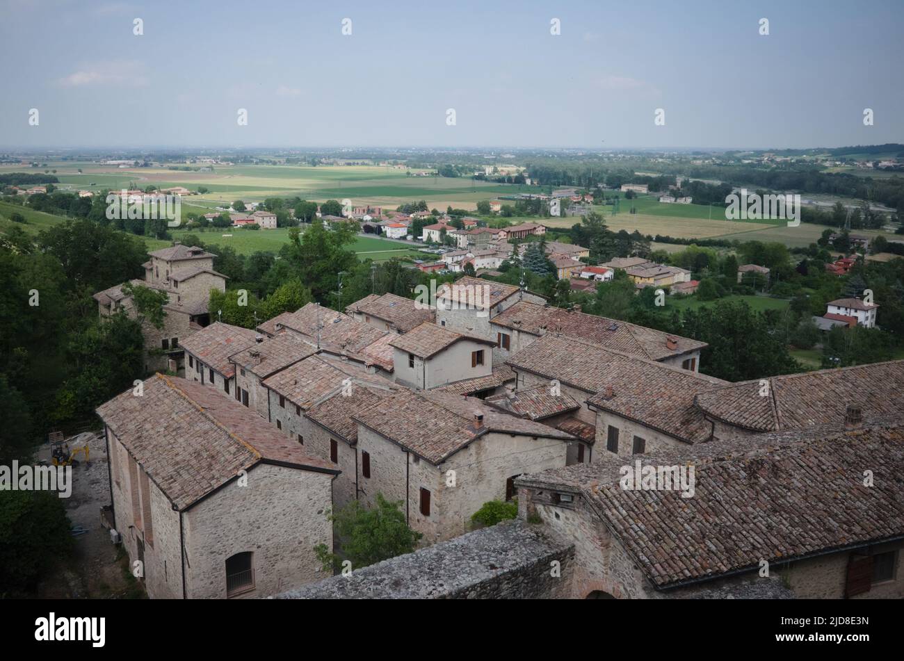Torrechiara, Parma, Italy - June, 2022: Top view of tiled rooftops of old houses in Italian village and valley with harvested agricultural fields Stock Photo