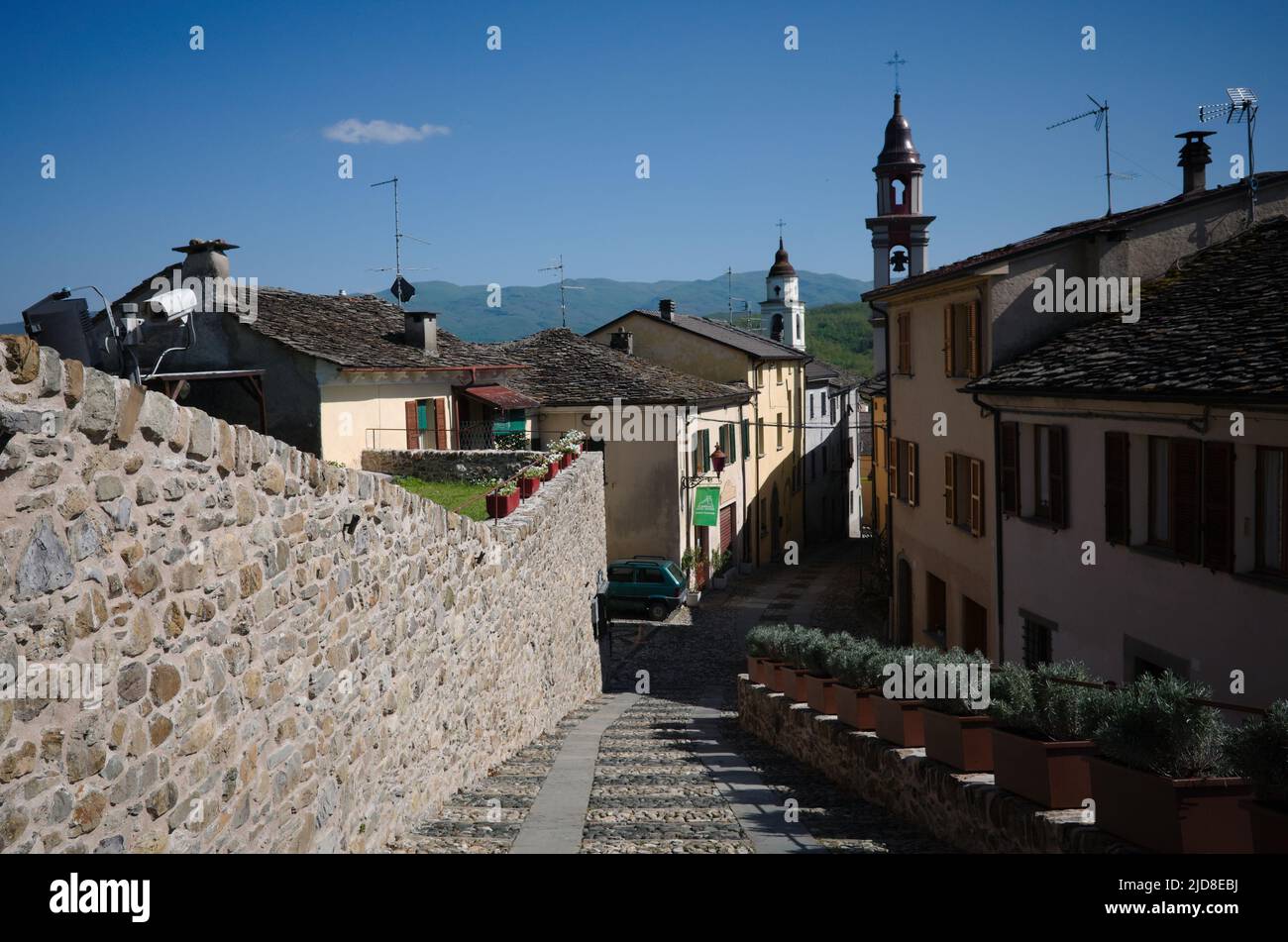 Compiano, Parma, Italy - May, 2022: Narrow cobbled street in Italian village. Typical Italian village with old houses with stone tiles and bell tower Stock Photo