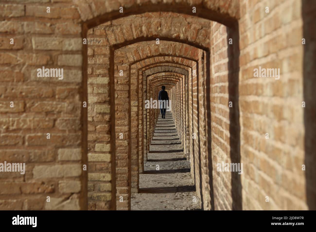 Allah-Verdi-Khan-Brücke in Isfahan, Iran. Auf persisch heißt sie Si-o-se Pol. Die Brücke hat zwei Etagen und überspannt den Zayandeh Rud. Die Brücke hat 33 Bögen. Eine Person geht durch den Bogengang, Stock Photo