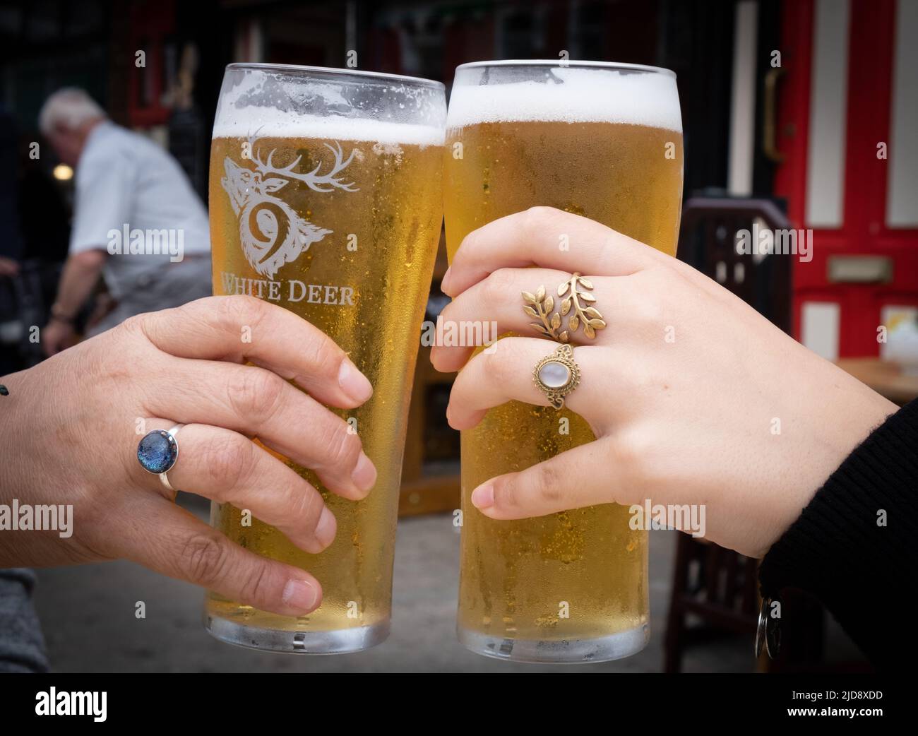 People celebrating with a toast cheers their glasses of beer pints together in a gesture of celebration. Stock Photo