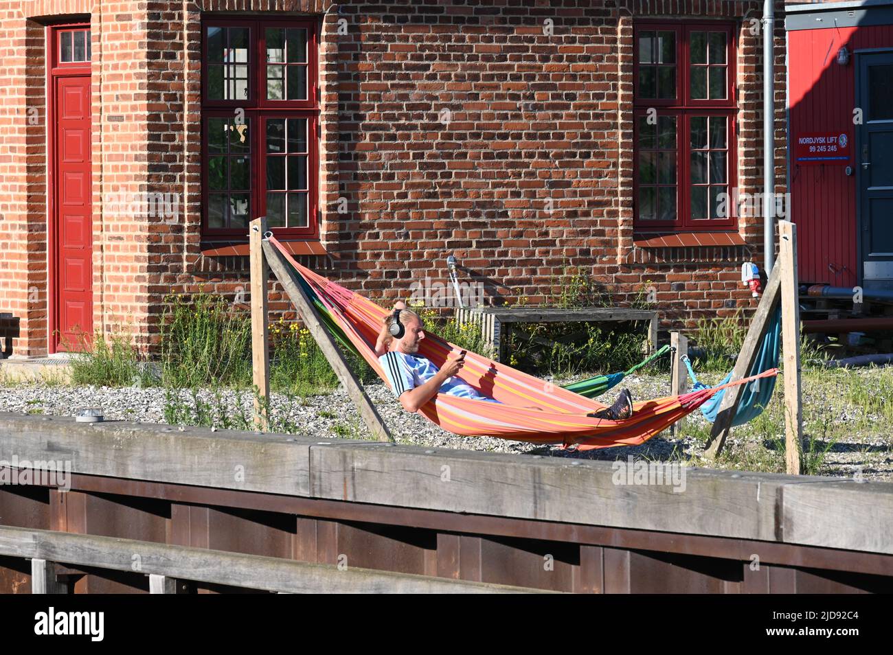 Man in a hammock in front of a red brick facade Stock Photo