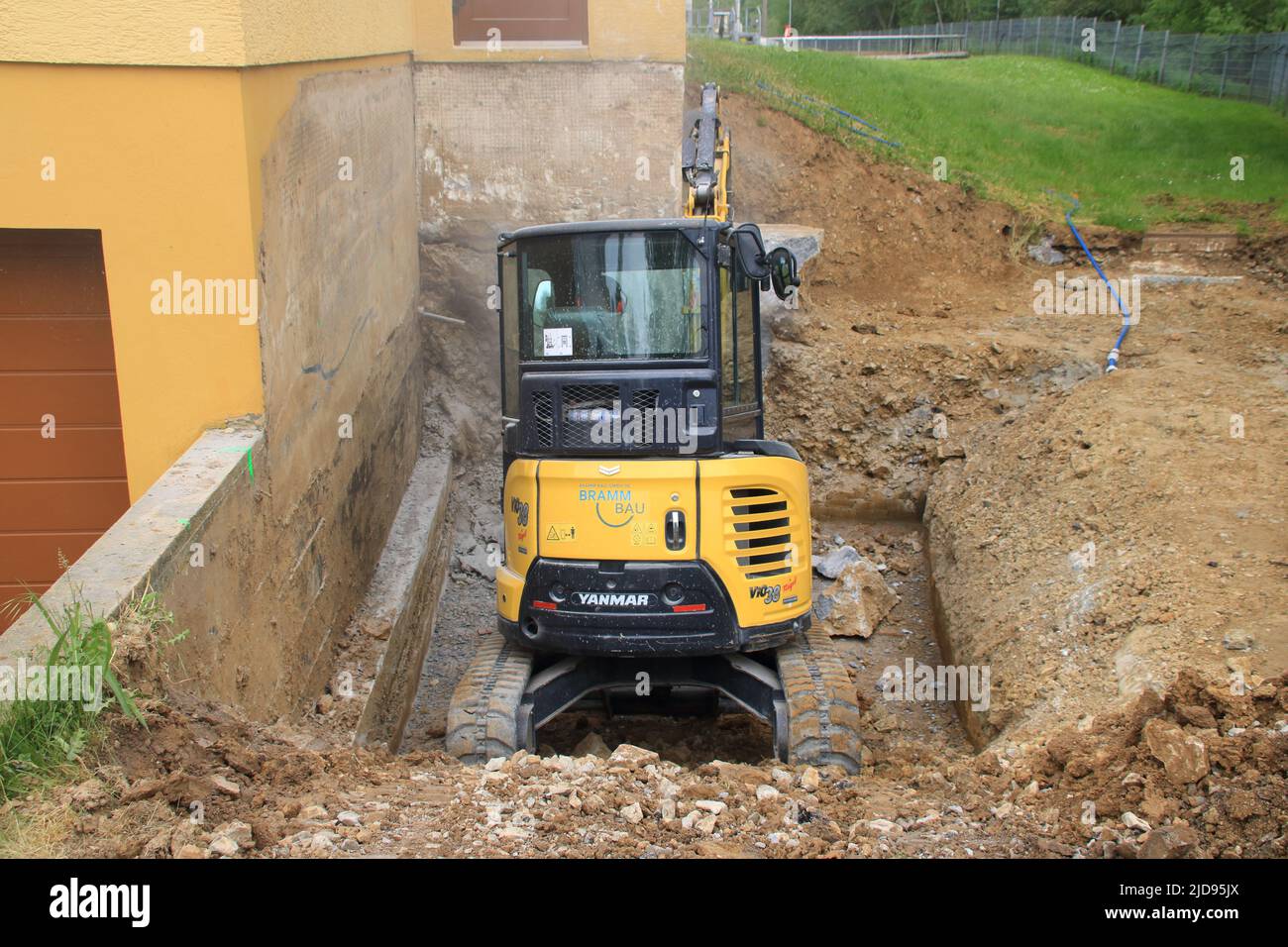 Excavator is in a pit and chisels on a house wall Stock Photo